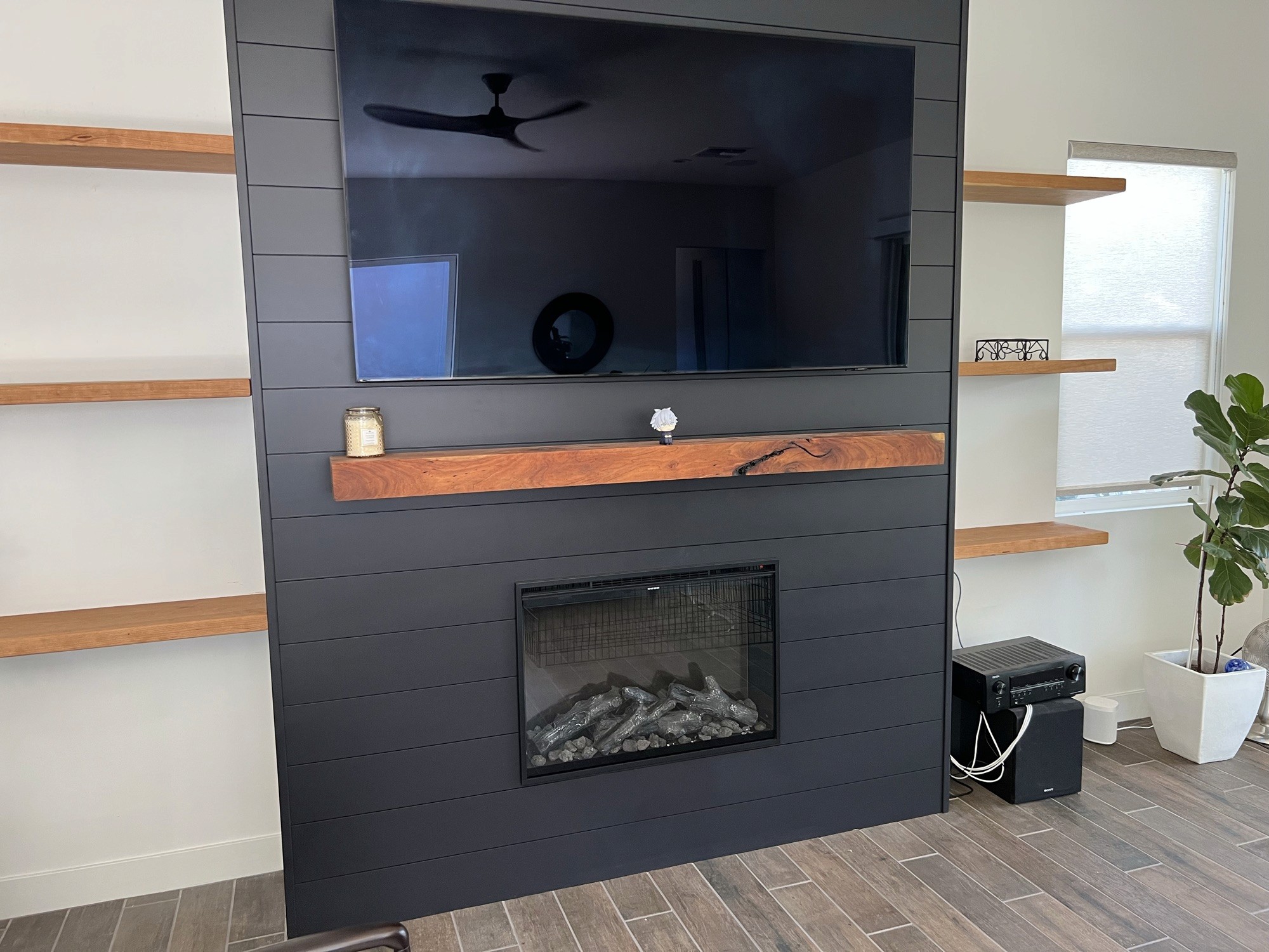 Shiplap media wall with floating shelves and a live-edge wood mantel